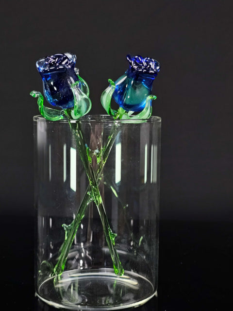 a glass vase with two blue roses in it